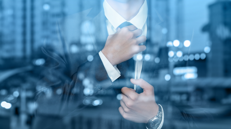Young businessman corrects a tie on the background of evening city