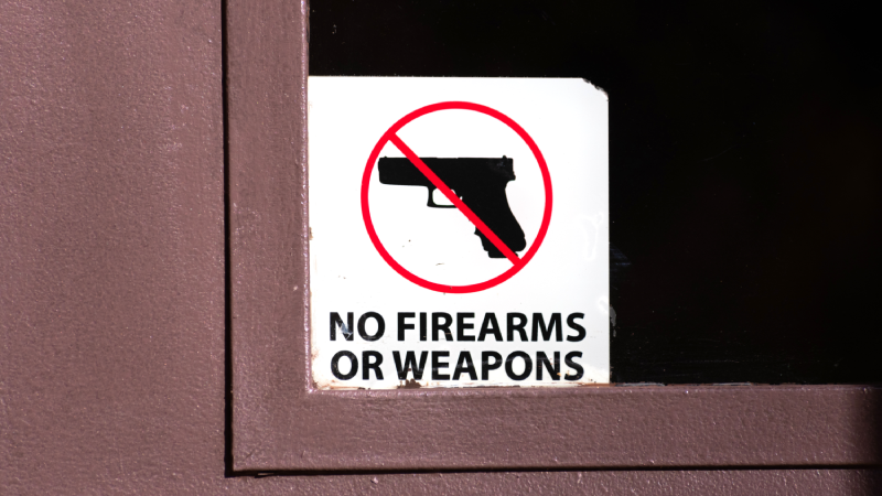No firearms or weapons sign on the glass entrance door to the business establishment notifies patrons that weapons aren't allowed, addresses security policy and protection concerns