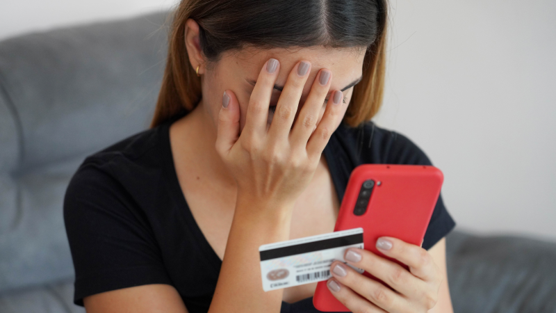 Digital theft. Desperate young woman finds out that her credit card was cloned and her bank account emptied. Cyber security concept