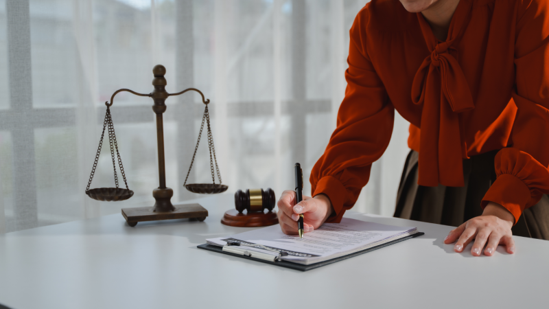 Lawyer working on a legal document with scales of justice and gavel on the table, representing the concept of law and justice