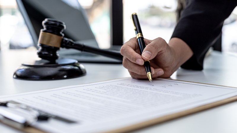 A male lawyer is signing a plea agreement with a client in a fraud case, in which the client has filed a lawsuit against an employee at a company that commits the fraud. Fraud litigation concept.