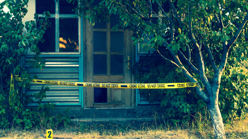 Crime scene tape near the house, police tape Do Not Cross outdoors