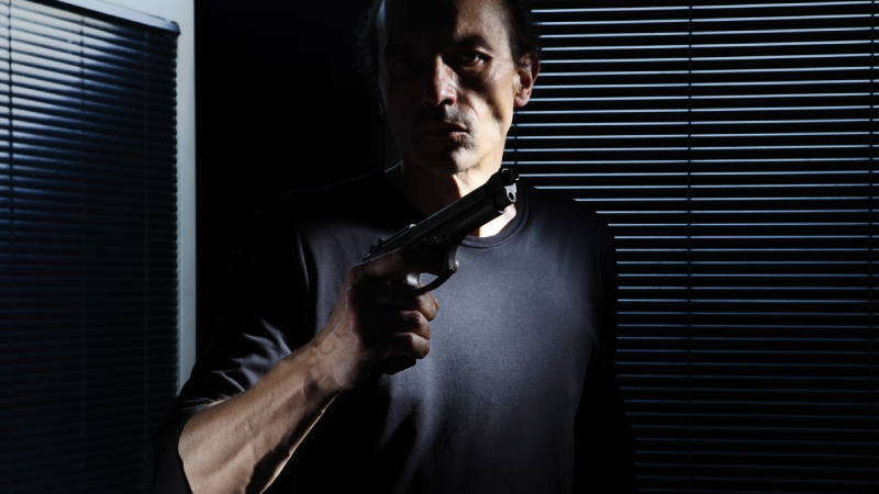 man with gun isolated on black door window, policeman, detective, bodyguard and self defense concept, otherwise robber, murderer and thief concept