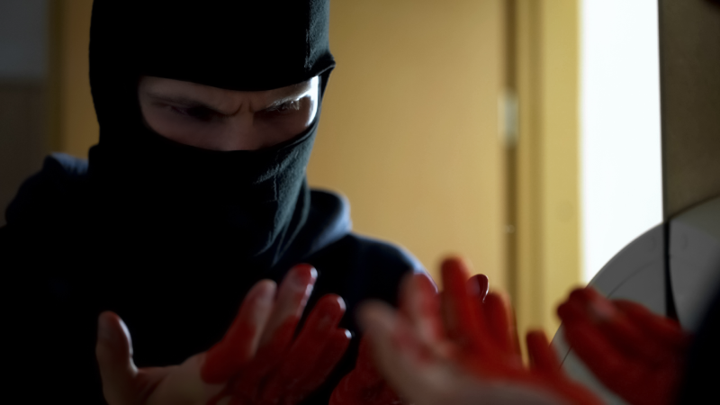 Manslaughter, professional robber looking at bloody hands in front of mirror