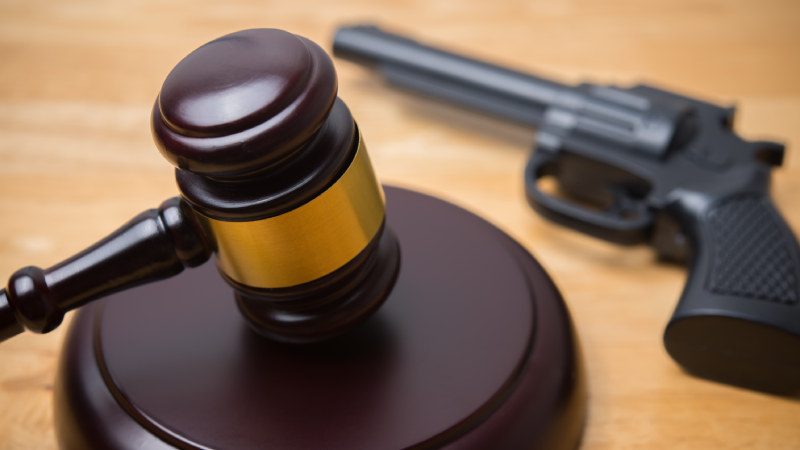Judge gavel and a handgun on wooden table background in courtroom. Gun law, gun charge, carrying a firearm without a permit, unlawful possession, crime and so on concept